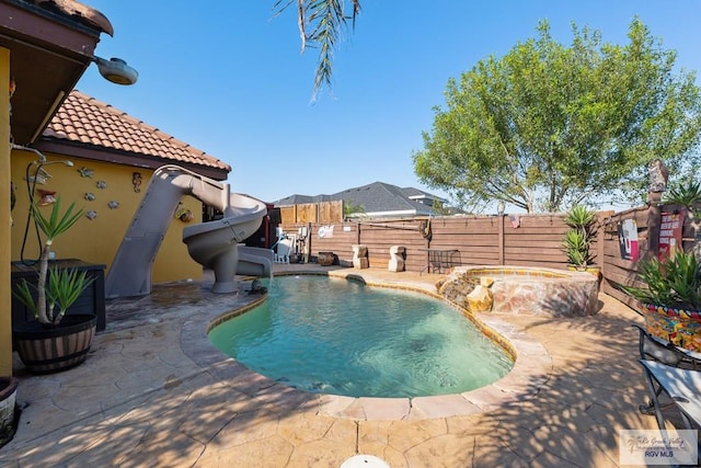 view of pool featuring pool water feature, a patio, an in ground hot tub, and a water slide