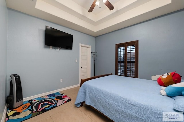 tiled bedroom with ceiling fan and a raised ceiling