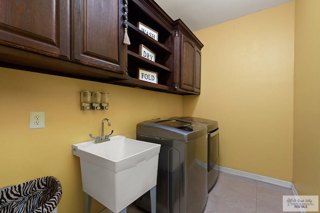 laundry area with sink, cabinets, washer and dryer, and light tile patterned floors