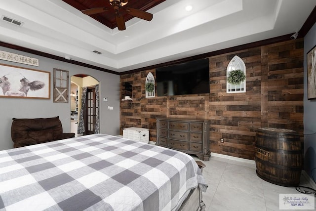 bedroom featuring ceiling fan, a tray ceiling, and wood walls