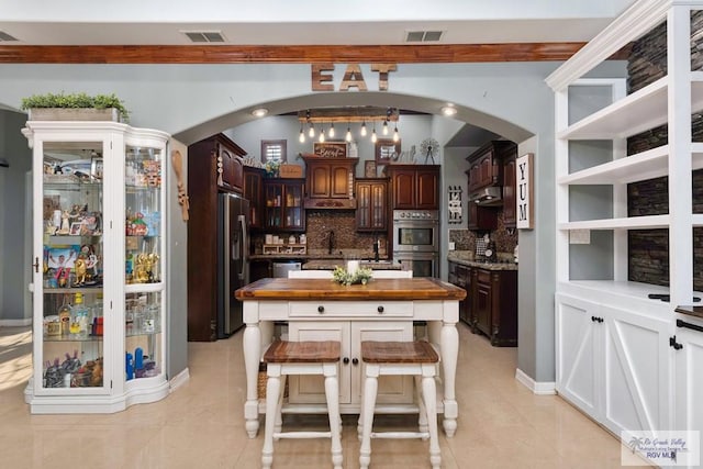 kitchen featuring sink, wooden counters, stainless steel appliances, dark brown cabinets, and tasteful backsplash