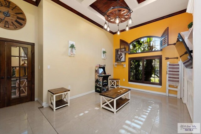 tiled entryway with a high ceiling, crown molding, and a notable chandelier