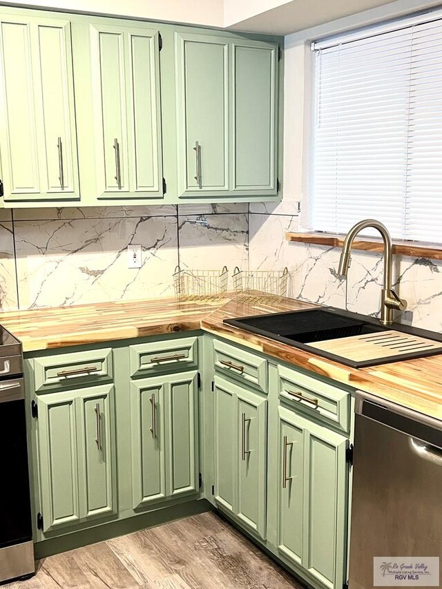 kitchen with green cabinets, butcher block counters, sink, and appliances with stainless steel finishes