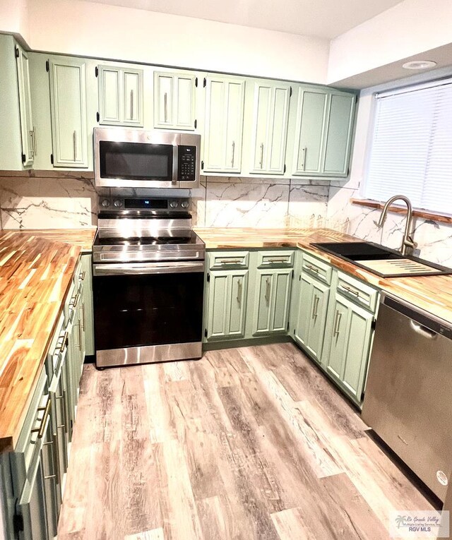 kitchen featuring stainless steel appliances, green cabinetry, butcher block counters, and sink