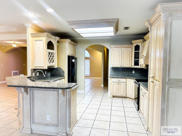 kitchen featuring stainless steel electric range oven, sink, tasteful backsplash, a kitchen breakfast bar, and black fridge