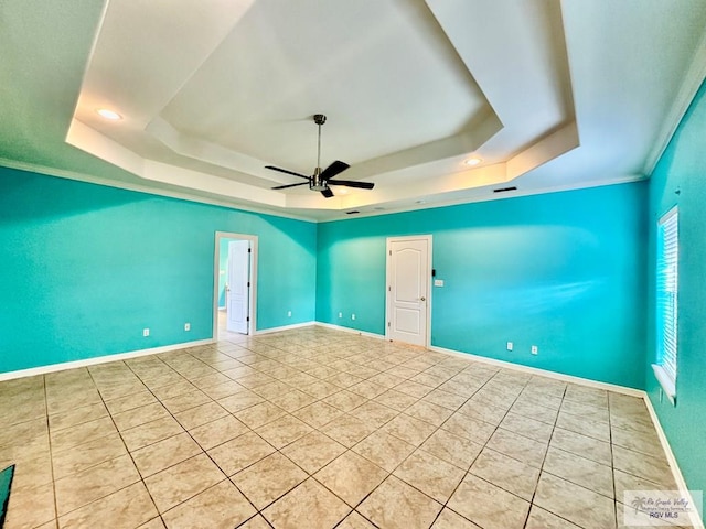 spare room with a raised ceiling, ceiling fan, and ornamental molding