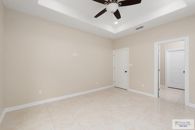 unfurnished bedroom with a tray ceiling, ceiling fan, and light tile patterned floors