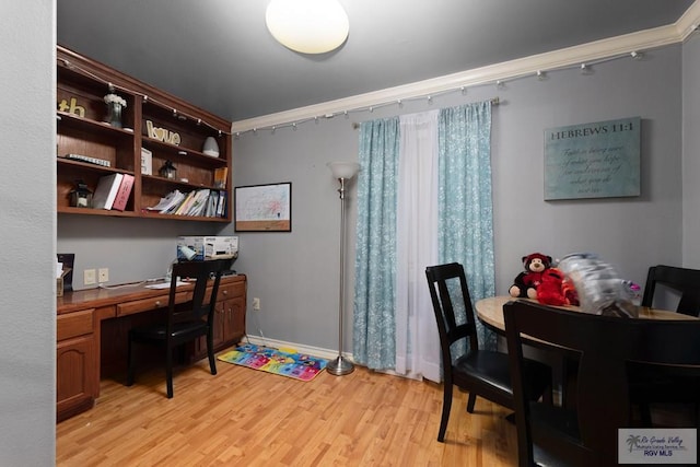 home office featuring crown molding, built in desk, and light wood-type flooring