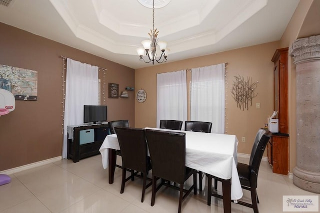 tiled dining room with an inviting chandelier and a tray ceiling