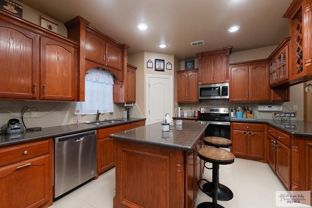 kitchen featuring sink, a breakfast bar area, dark stone countertops, stainless steel appliances, and a center island