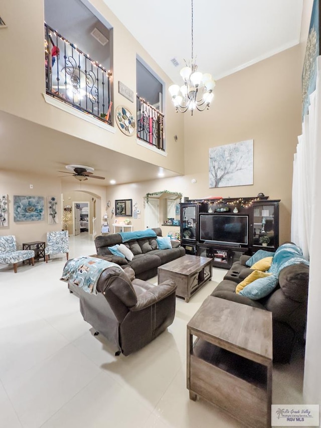 tiled living room with a towering ceiling and ceiling fan with notable chandelier