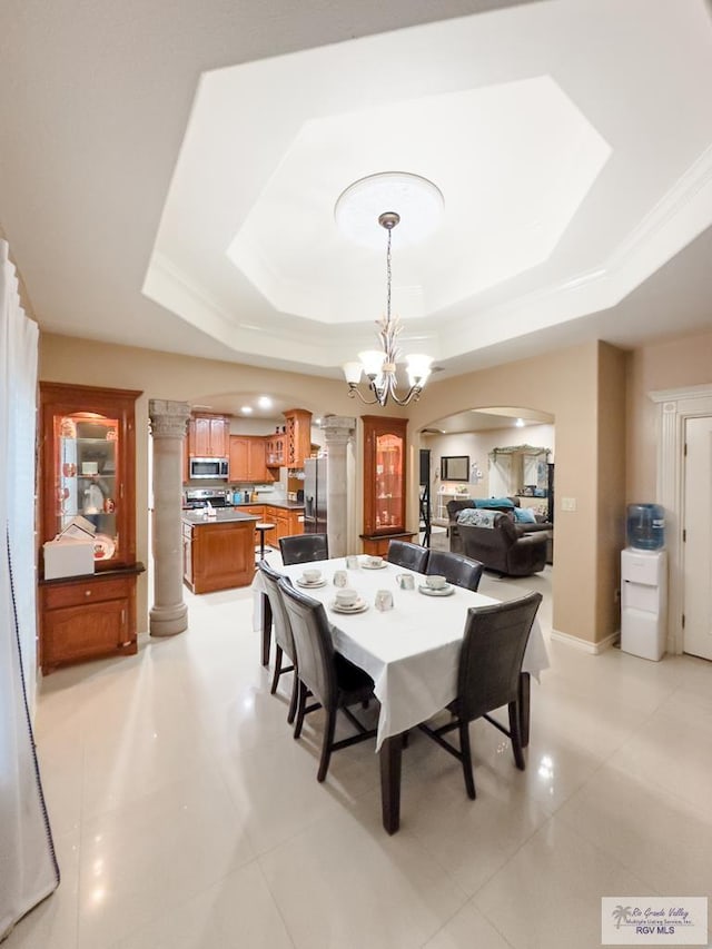 dining area with a raised ceiling, light tile patterned floors, ornamental molding, and an inviting chandelier