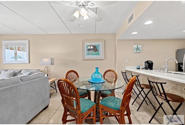 tiled dining room with ceiling fan and sink