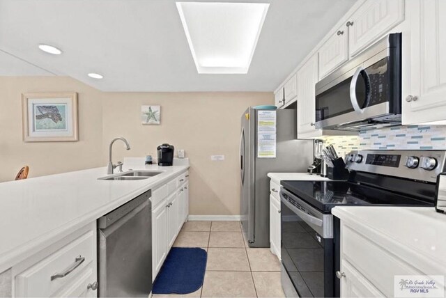 kitchen featuring tasteful backsplash, stainless steel appliances, sink, light tile patterned floors, and white cabinetry