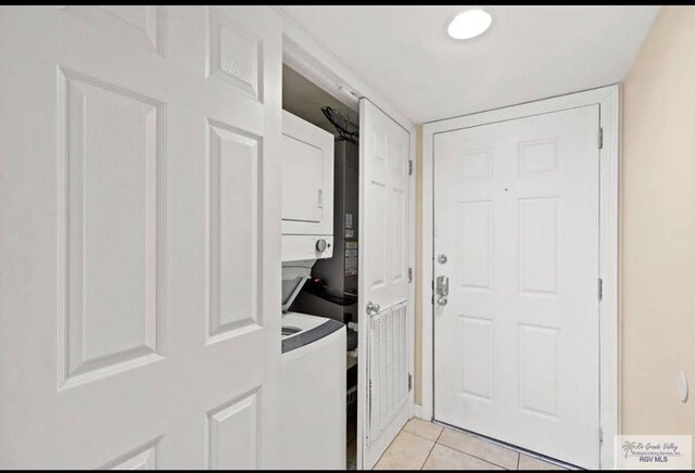 laundry room featuring stacked washer / drying machine and light tile patterned flooring