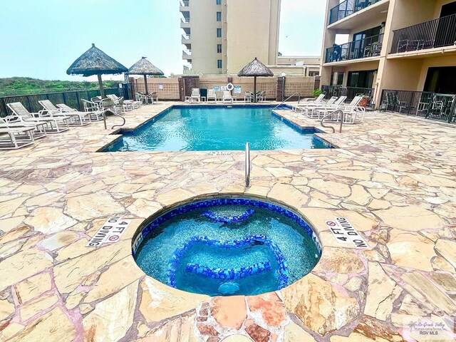 view of pool with a community hot tub and a patio