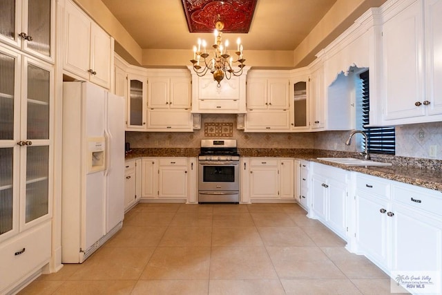 kitchen with white refrigerator with ice dispenser, a sink, stainless steel gas range, backsplash, and light tile patterned flooring