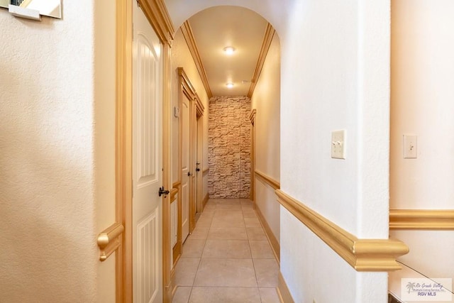 corridor featuring arched walkways and light tile patterned floors