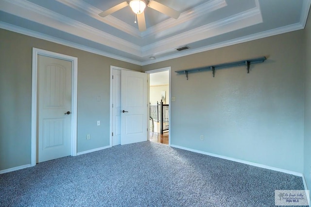 unfurnished bedroom featuring carpet floors, a raised ceiling, visible vents, and crown molding