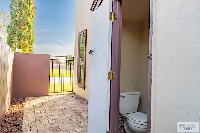 bathroom with toilet and brick floor