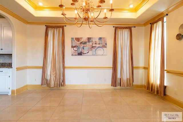 unfurnished dining area with a tray ceiling, arched walkways, and crown molding