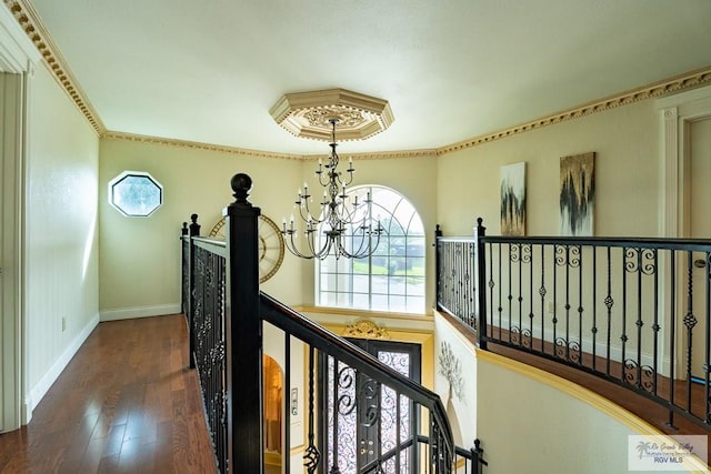 corridor with crown molding, an inviting chandelier, an upstairs landing, wood finished floors, and baseboards