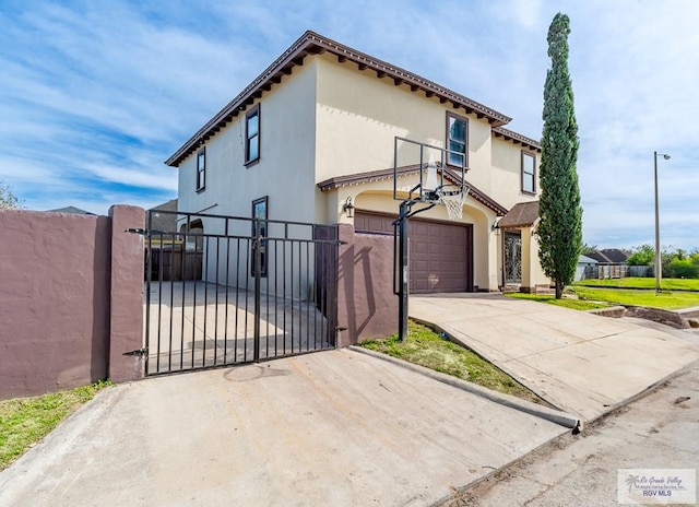 view of front of house with a gate, driveway, fence, and stucco siding