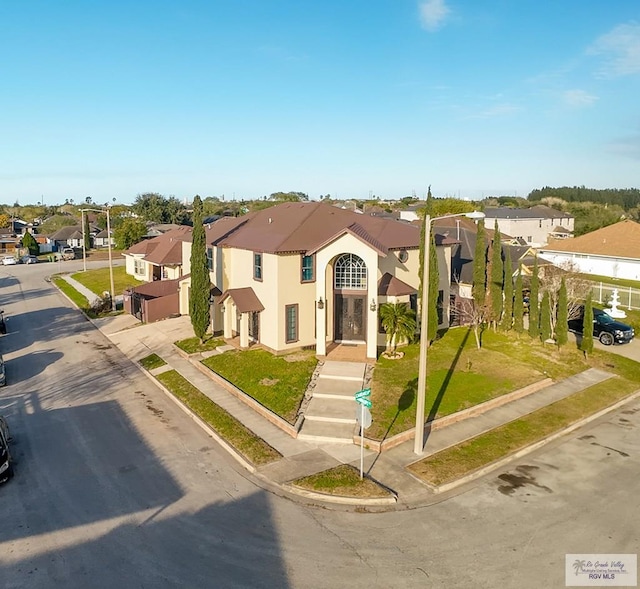 view of front of home with a front yard, a residential view, and stucco siding