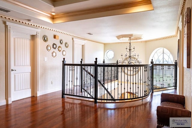 hallway featuring a notable chandelier, visible vents, ornamental molding, and wood finished floors