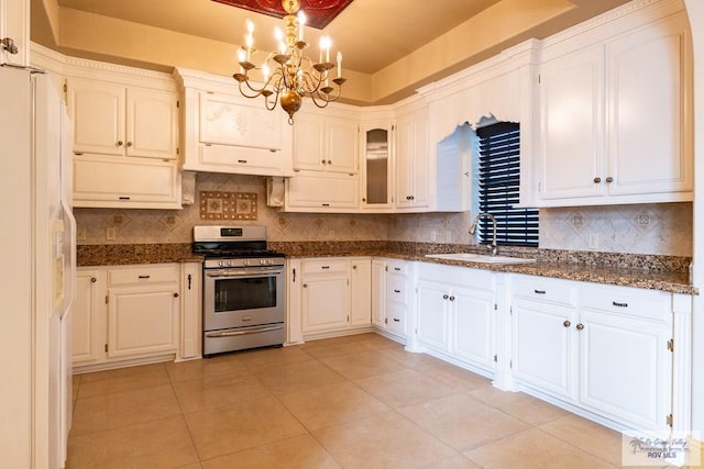 kitchen featuring a sink, stainless steel gas range, white fridge with ice dispenser, tasteful backsplash, and a raised ceiling