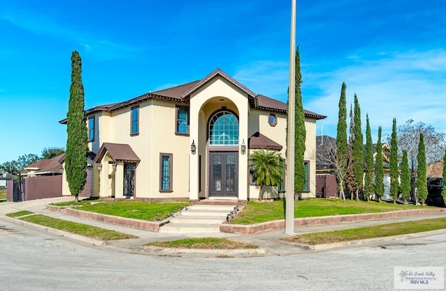 mediterranean / spanish-style home with french doors, a front lawn, and stucco siding