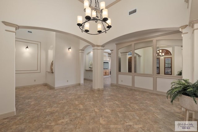 5713 Spicewood, Harlingen, TX 78552 - unfurnished room featuring arched walkways, decorative columns, a chandelier, a towering ceiling, and stone finish floors