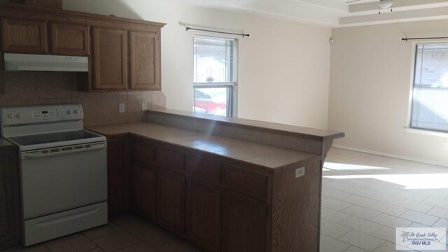 kitchen with electric range, ceiling fan, backsplash, kitchen peninsula, and dark tile patterned flooring