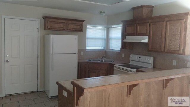 kitchen with sink, white appliances, kitchen peninsula, and a breakfast bar area