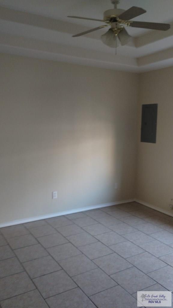 empty room featuring ceiling fan, light tile patterned floors, and electric panel