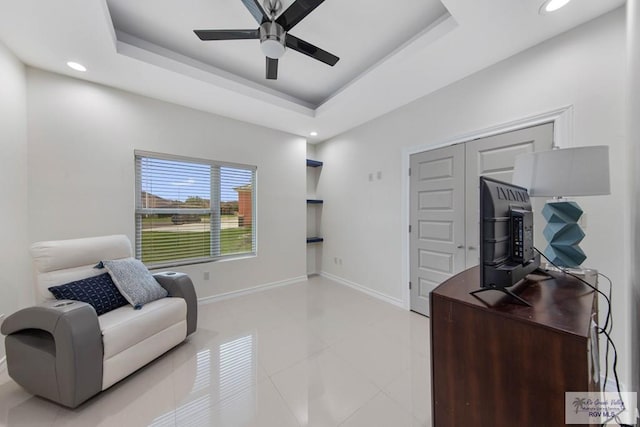 sitting room featuring ceiling fan, light tile patterned flooring, and a raised ceiling