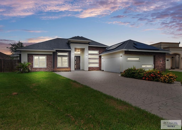 prairie-style home with solar panels, a garage, and a lawn