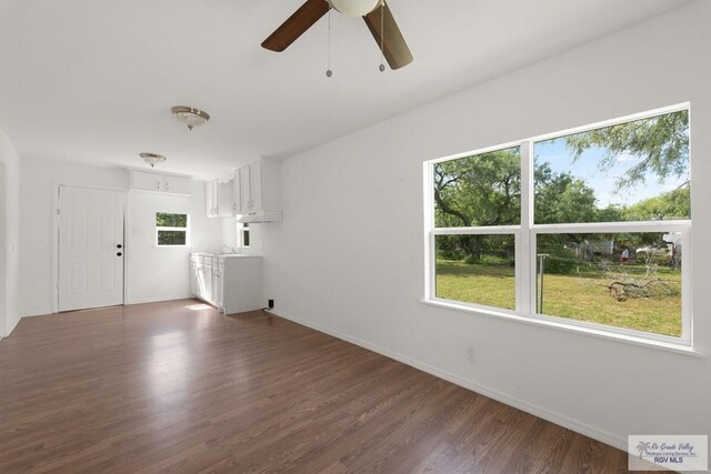 unfurnished living room with ceiling fan and dark wood-type flooring