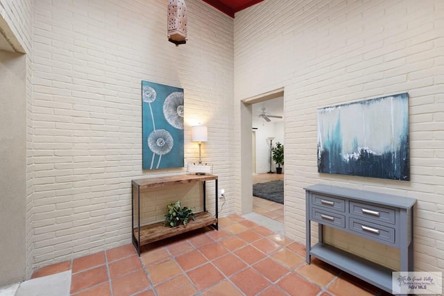 hallway featuring brick wall, a high ceiling, and tile patterned floors