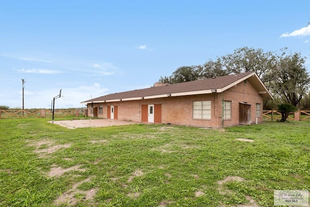 view of front facade with brick siding, a fenced backyard, a patio, and a front yard