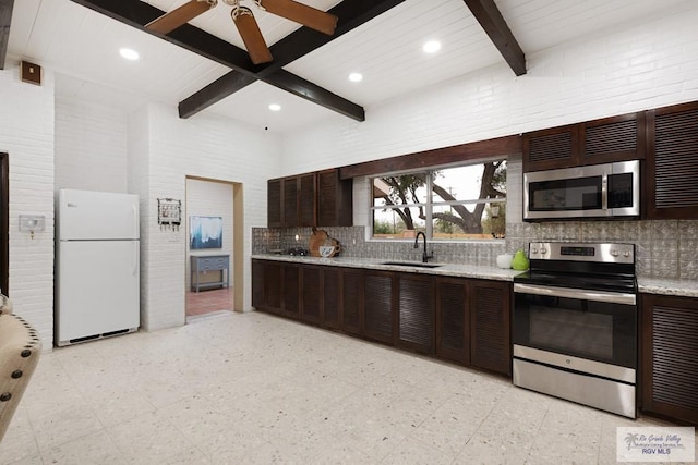 kitchen with stainless steel appliances, beam ceiling, a sink, and light floors