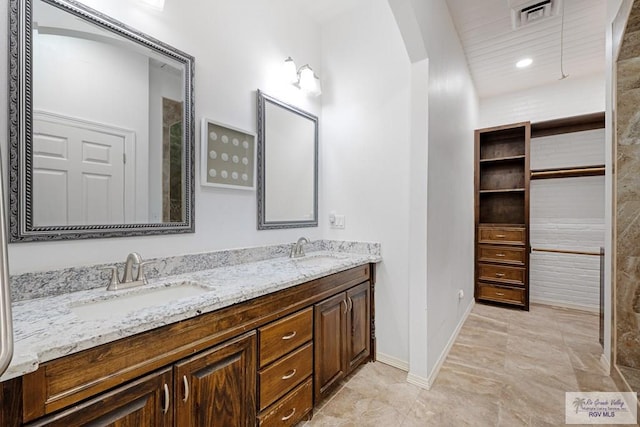 bathroom with double vanity, a sink, visible vents, and baseboards