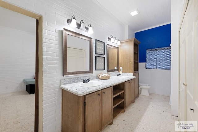 bathroom with toilet, double vanity, a sink, and tile patterned floors