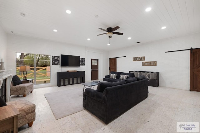 living room with brick wall, a barn door, a fireplace, and recessed lighting