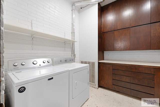 washroom with laundry area, brick wall, visible vents, and independent washer and dryer