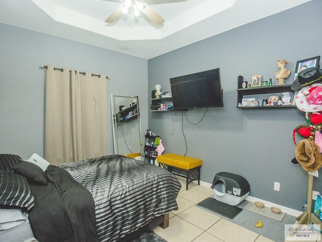 tiled bedroom with a raised ceiling and ceiling fan