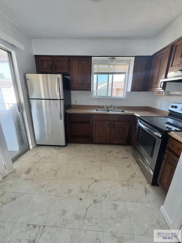 kitchen with a sink, stainless steel appliances, dark brown cabinetry, and marble finish floor