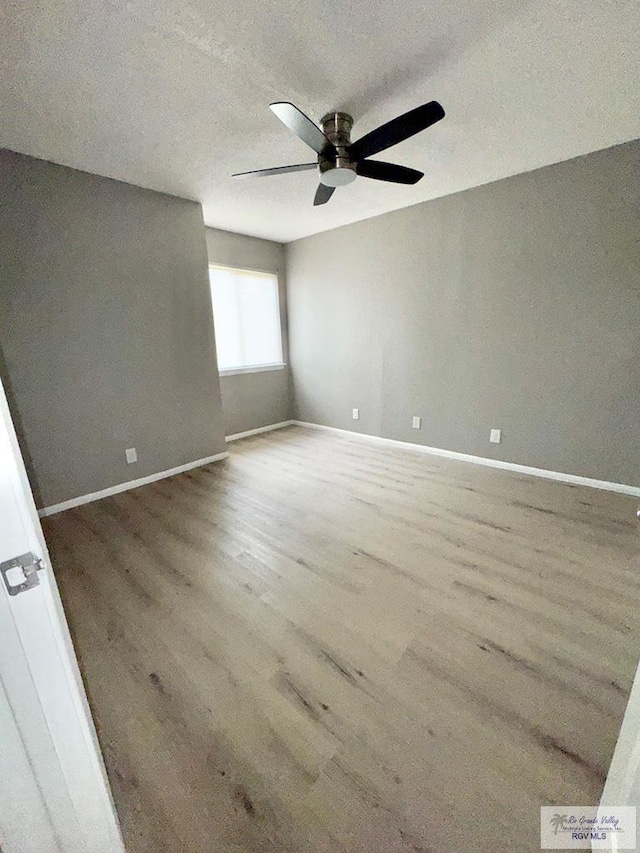 unfurnished room featuring a ceiling fan, wood finished floors, and baseboards