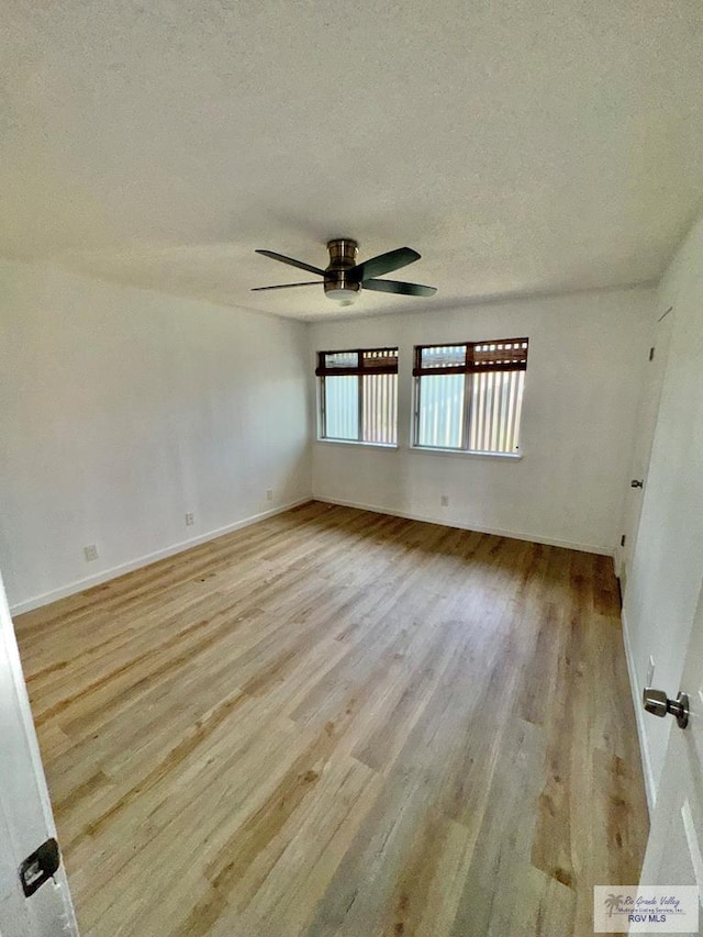 spare room with wood finished floors, a ceiling fan, baseboards, and a textured ceiling