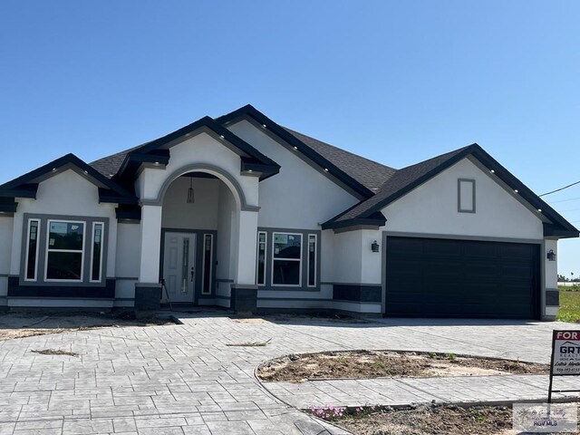 32660 Jorge St, Los Fresnos, TX 78566 - view of front of property featuring stucco siding, decorative driveway, a garage, and a shingled roof